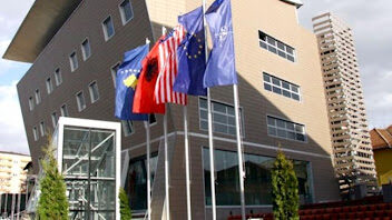 A row of flags in front of a building Description automatically generated with low confidence