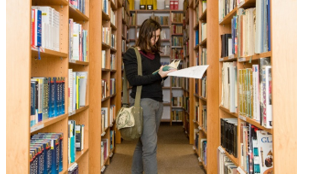 Slika 1: Dijakinja med policami šolske knjižnice DGM (vir: arhiv DGM, 2015)