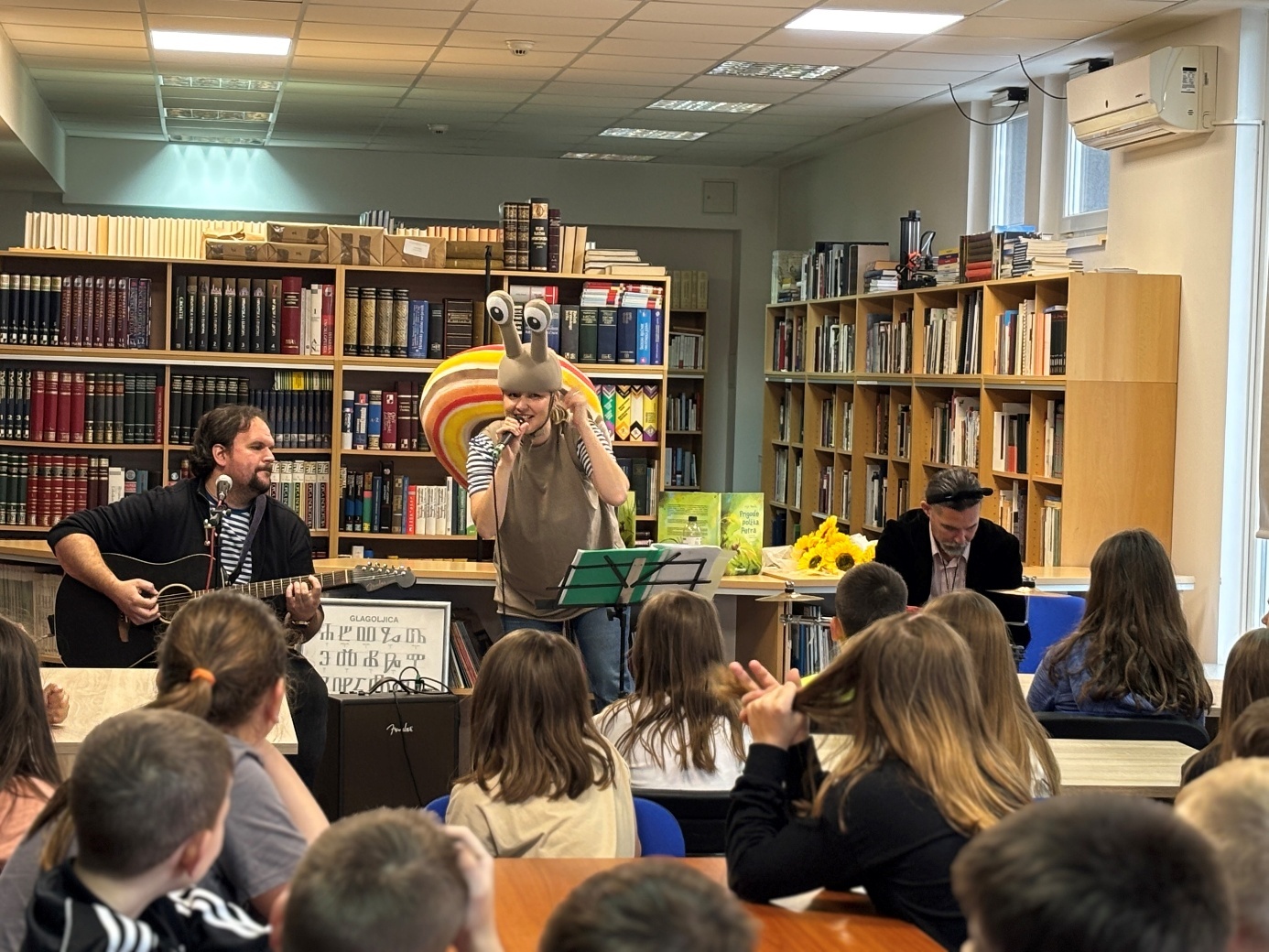 Slika 1: Nastop Anje Pavlin, Jana Medleta in Primoža Malenška z glasbeno pravljico Prigode polžka Petra v Mestni knjižnici in čitalnici Ivana Belostenca, Ozalj (arhiv Knjižnice Mirana Jarca in Mestne knjižnice »Ivan Goran Kovačić«)